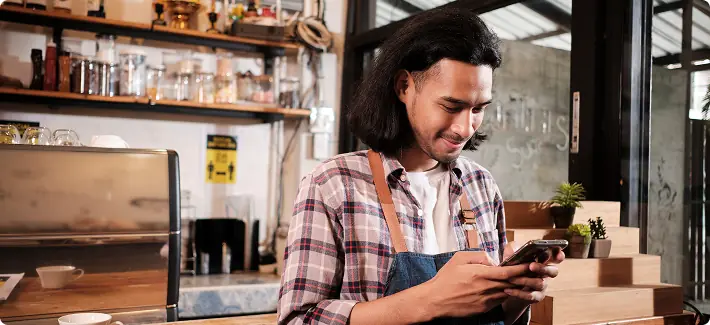 Empreendedor em uma cafeteria acompanhando resultados no celular