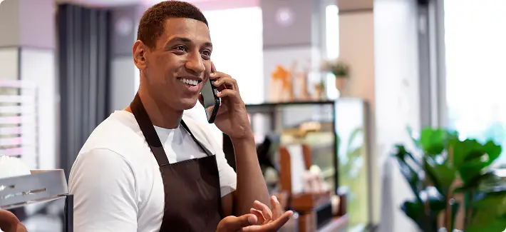 Atendente de uma loja de bairro falando ao telefone com um cliente