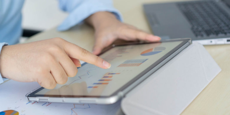 Mão do empresário usa tablet digital e abre o relatório financeiro para verificar as estatísticas de negócios