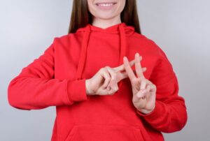 Mulher de roupa vermelha fazendo o sinal de hashtag com as mãos