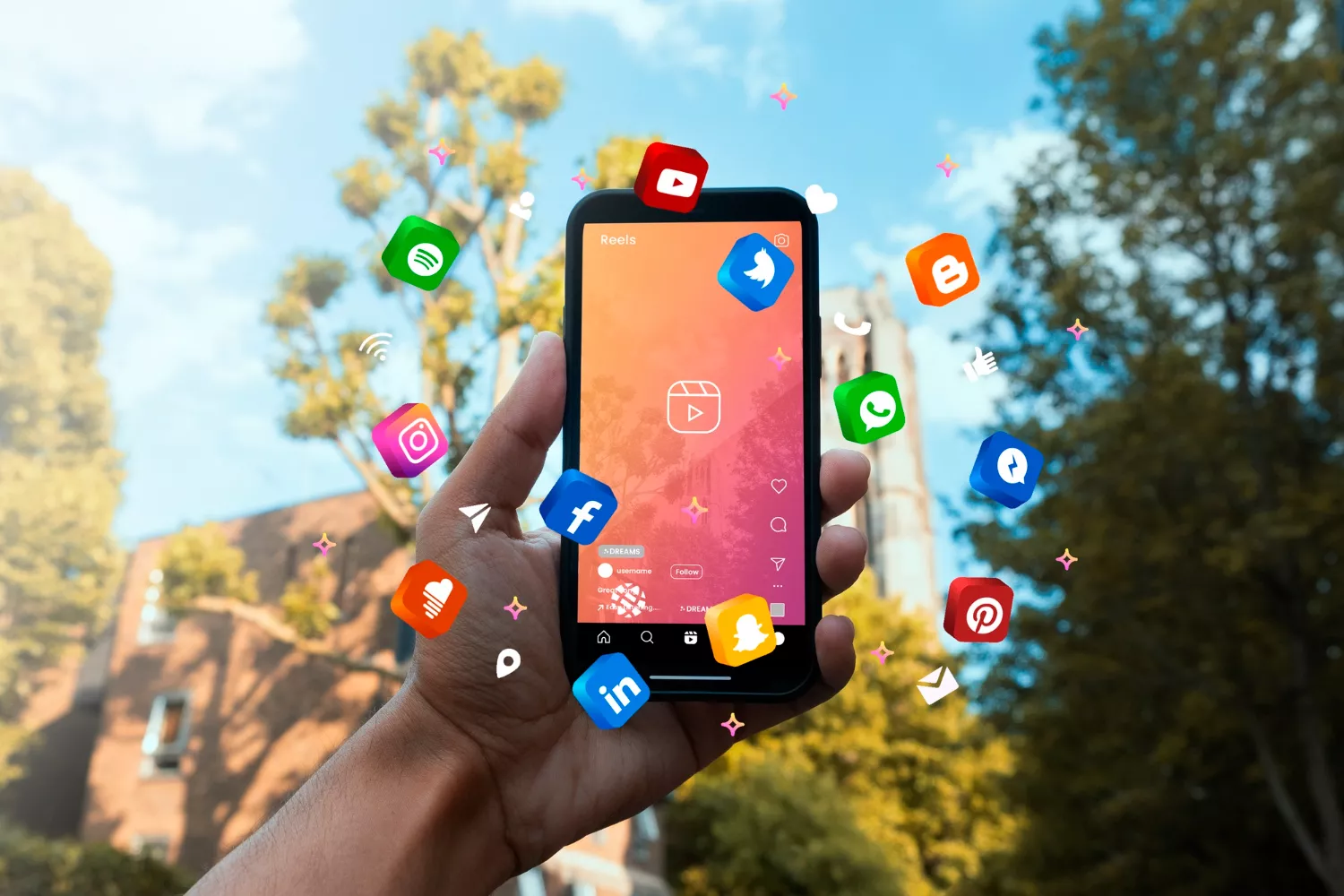 Mão segurando um smartphone com a tela aberta no Instagram Reels, rodeado por ícones flutuantes, fazendo alusão ao marketing de redes sociais